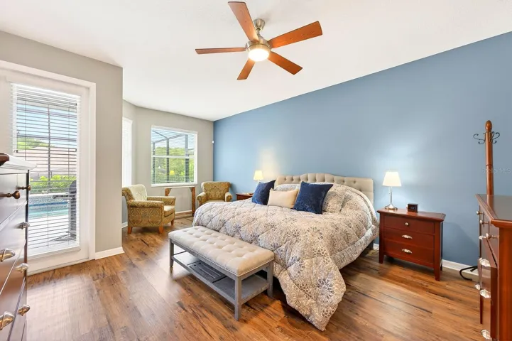 The generous Primary Suite serves as a luxurious retreat, featuring luxury vinyl plank flooring, a sitting area overlooking the pool, PRIVATE ACCESS TO THE LANAI, dual closets—including a walk-in closet—and a SPACIOUS EN SUITE BATH.
