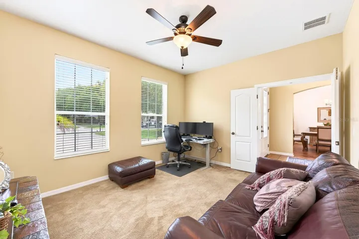 FRENCH DOORS open to a VERSATILE DEN/OFFICE, perfect for working from home, a library, hobby room, or flex space.