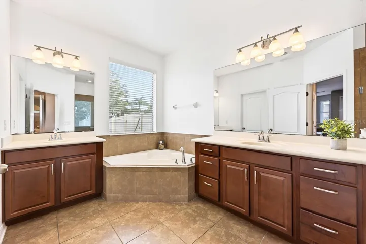 A SPACIOUS PRIMARY EN SUITE BATH boasts split vanities, a garden tub, step-in shower, and private water closet.
