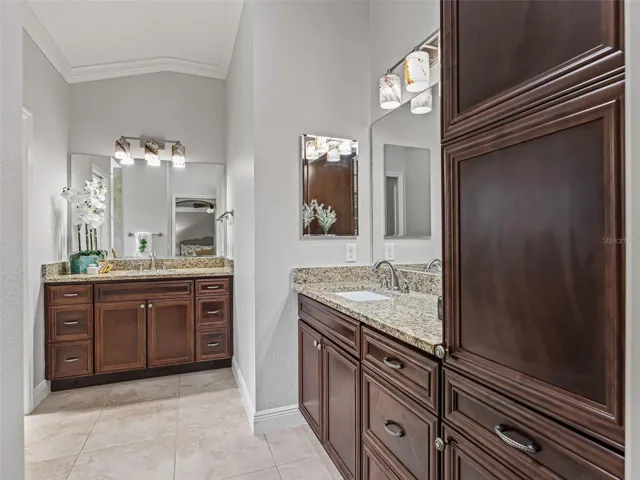 Primary bath with roman shower, dual vanities, crown moulding, additional cabinetry