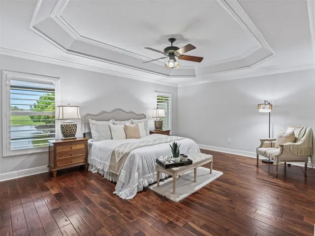 Primary suite with tray ceiling, hand scraped wooden floors, plantation shutters