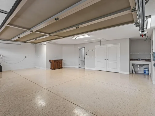 oversized large garage with epoxy floor, sink, and golf cart bay.  Additional screen enclosure for garage
