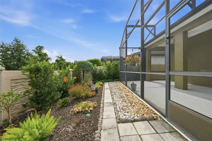 Stunning garden beds and paver walkway surrounding rear screen patio