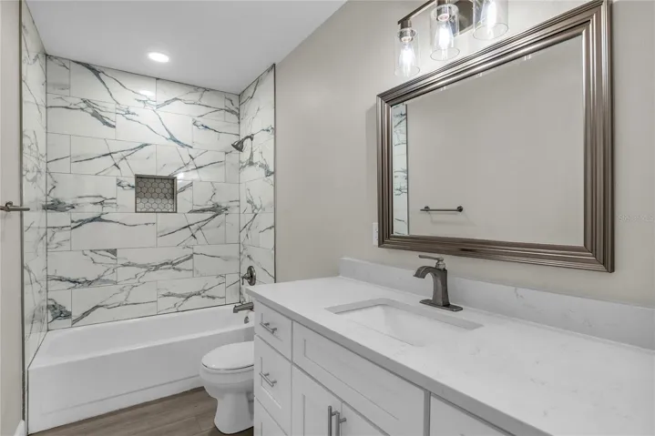Full bath features modern finishes with a tiled shower/tub combo and quartz vanity