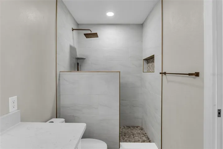 Primary ensuite bath features a tile walk-in shower, quartz vanity and modern finishes