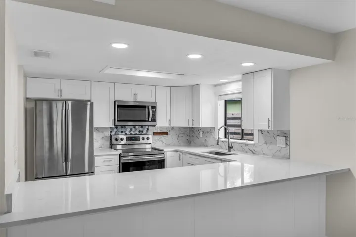Updated kitchen with shaker cabinets, quartz countertops, tile backsplash and stainless steel appliances