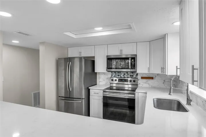 Updated kitchen with shaker cabinets, quartz countertops, tile backsplash and stainless steel appliances