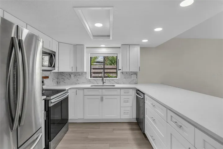 Updated kitchen with shaker cabinets, quartz countertops, tile backsplash and stainless steel appliances
