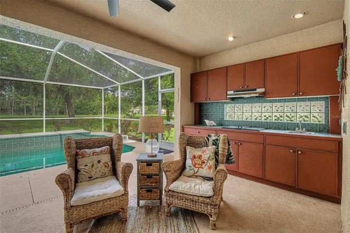 A true outdoor kitchen with cooktop and sink with custom cabinets and backsplash