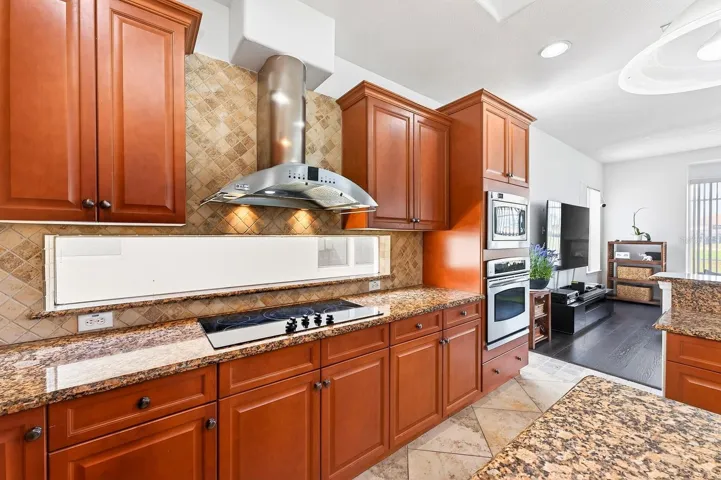 An ABUNDANCE OF CABINETRY and GRANITE COUNTERTOPS provide ample workspace, along with features such as a center island, tile backsplash, closet pantry, extended breakfast bar, and stainless steel appliances.