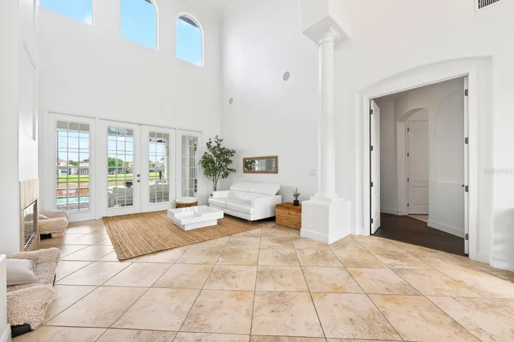 The formal Living Room is both elegant and inviting, featuring a COZY FIREPLACE and FRENCH DOORS that open directly to the outdoor living space.