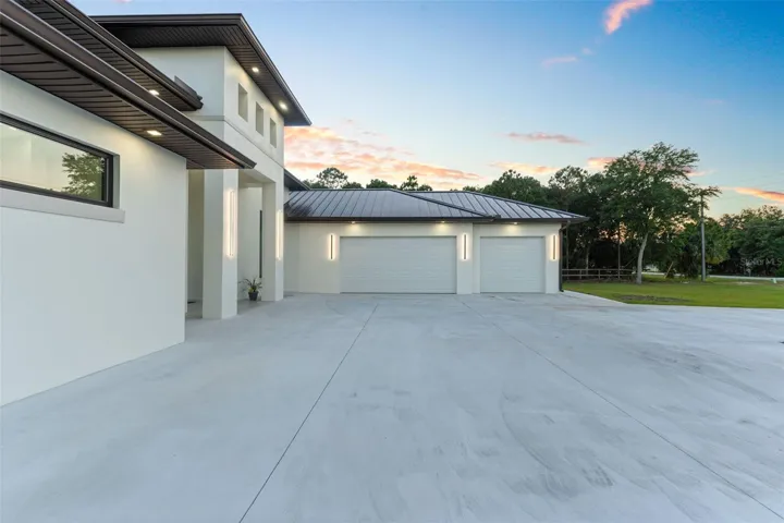 Paver driveway leading to a spacious garage and welcoming entryway
