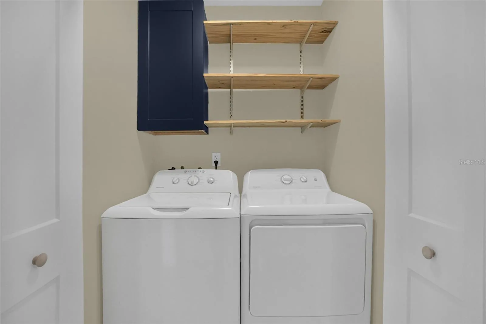 Laundry closet with shelving for additional storage and organization.