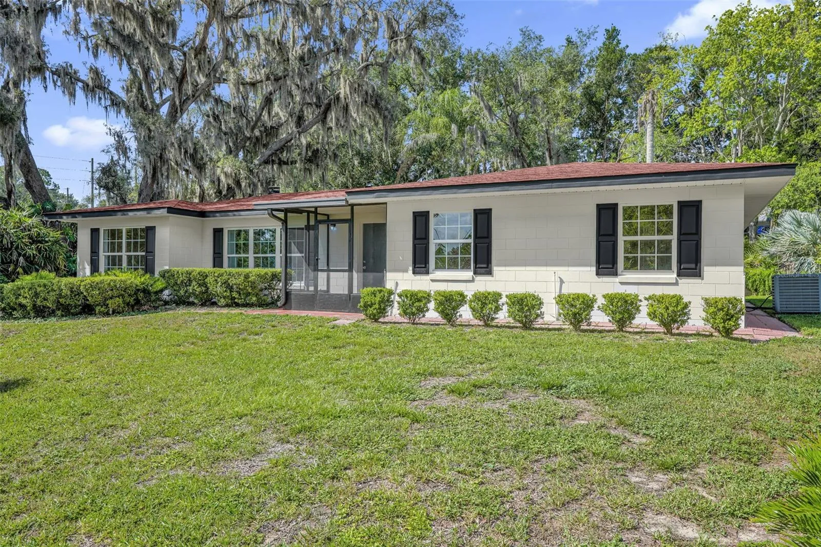 Front exterior showcasing replacement windows (2026), mature oak trees, decorative paver walkway, and fresh landscaping.