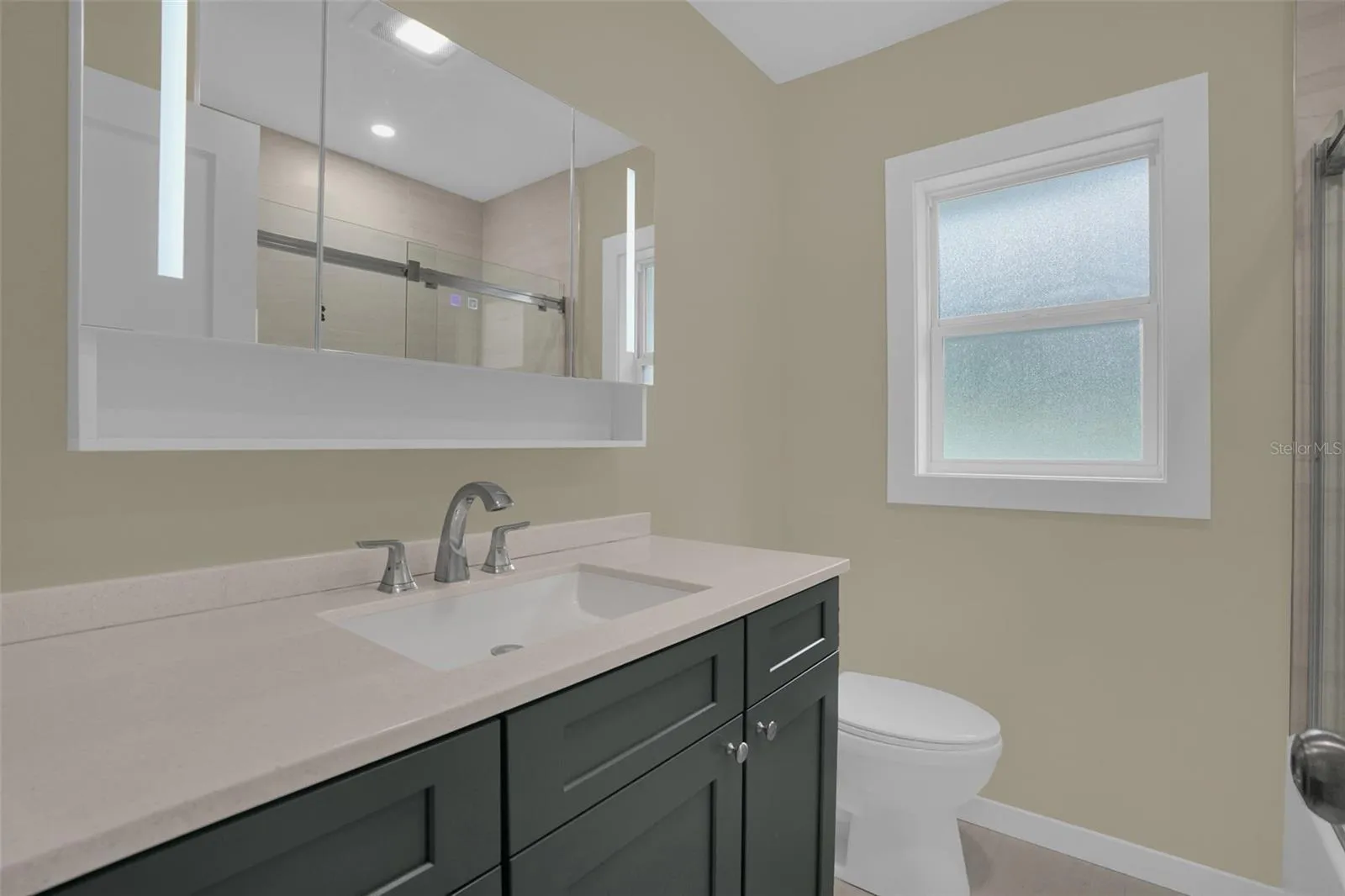 Beautifully remodeled guest bathroom featuring modern vanity, smart mirror, and updated finishes.