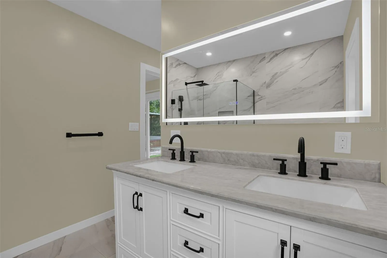 Dual-sink vanity with smart LED mirror, modern fixtures, and updated cabinetry.