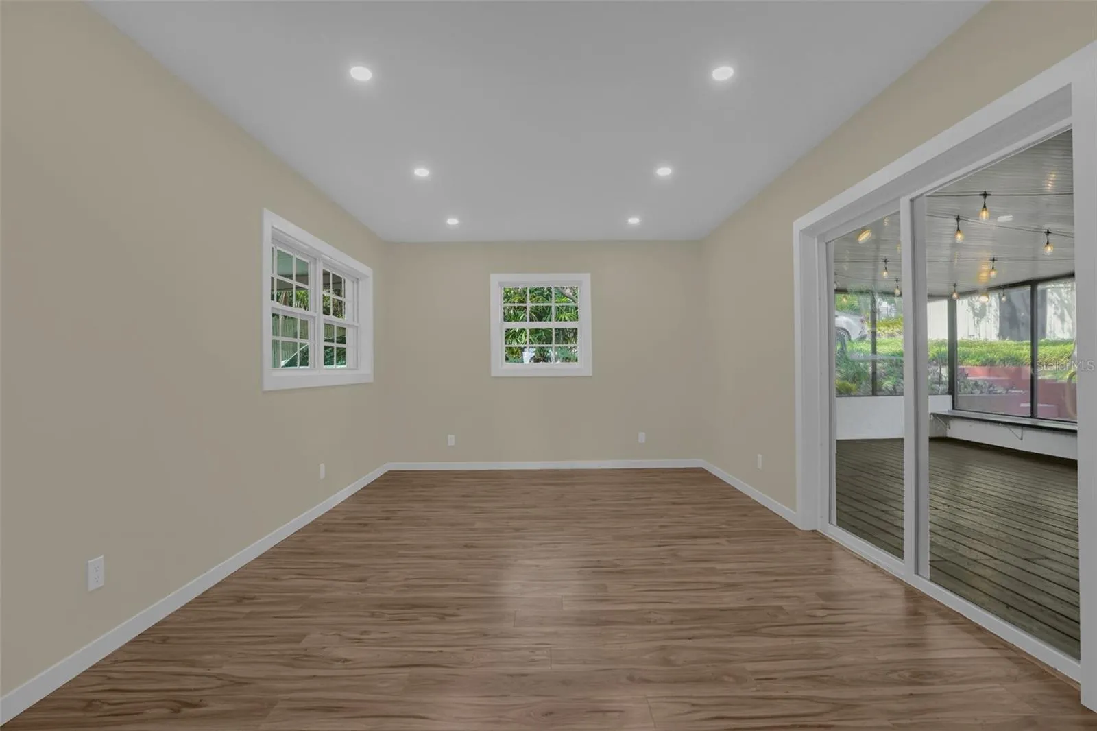 Versatile bonus room with updated laminate flooring (2025) and direct access to the outdoor living area.
