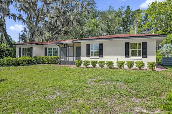 Front exterior showcasing replacement windows (2026), mature oak trees, decorative paver walkway, and fresh landscaping.