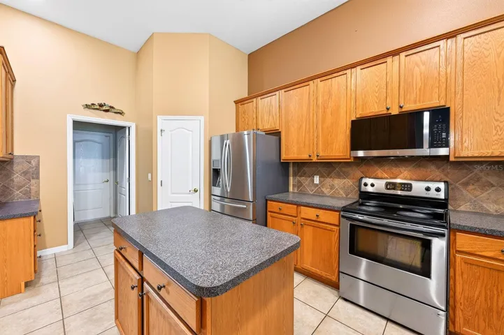 Home chefs will love the STAINLESS STEEL APPLIANCES, breakfast bar seating, prep ISLAND, pantry storage, tiled backsplash, and abundant cabinet and counter space.