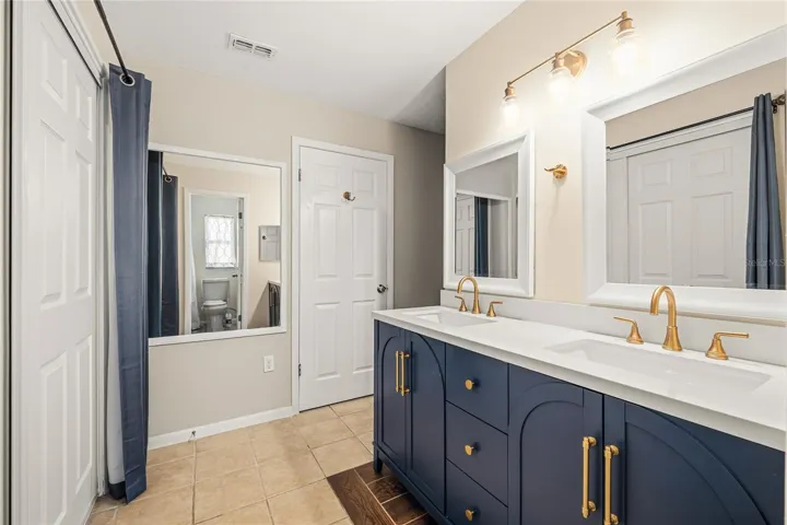 Renovated primary bath includes new plumbing, double vanity with quartz countertop and dressing mirror