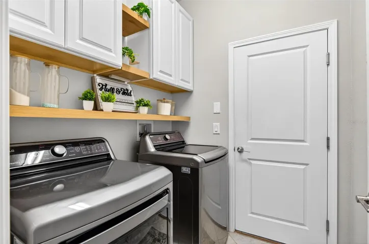 Laundry room with electric washer/dryer hook ups and additional shelving/cabinet space
