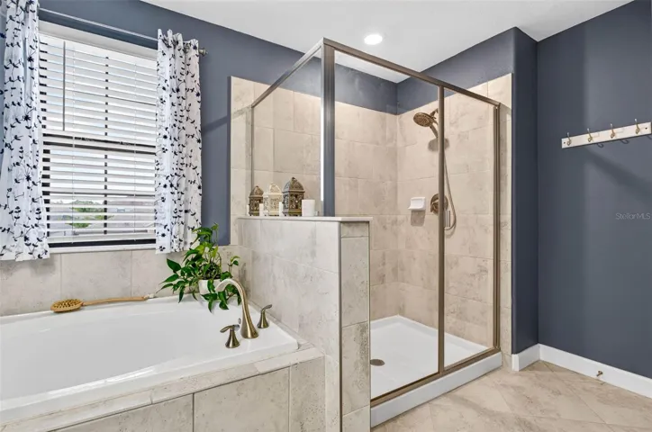 Primary en suite bathroom with garden tub, walk in shower, blinds and private wash closet