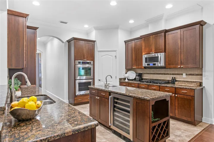 The kitchen is a true gathering space, featuring abundant countertop prep space, a pantry, gas range, wine refrigerator and additional bar sink