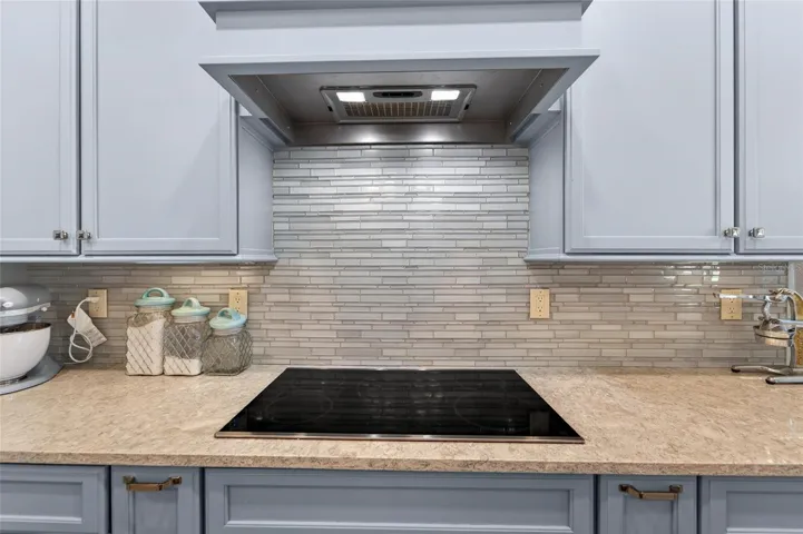Cook top range with hood and glass tile backsplash