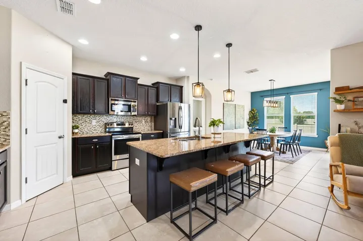 At the heart of the home, the UPGRADED KITCHEN is designed to impress with rich cabinetry, sleek granite countertops, STAINLESS STEEL APPLIANCES, a complementary backsplash, pantry storage, and a large center ISLAND with bar seating.