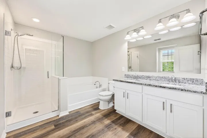 A STYLISH EN SUITE BATH boasts dual sinks, a garden tub, and a separate step-in shower.