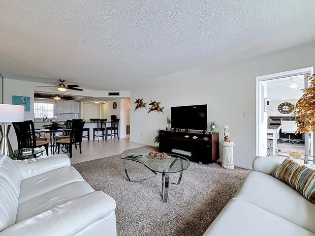 Open and airy living area that flows effortlessly from the dining room, highlighted by contemporary decor and warm sunlight and a serene view.