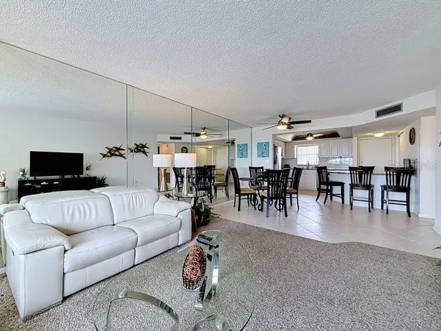 Open and airy living area that flows effortlessly from the dining room, highlighted by contemporary decor and warm sunlight and a serene view.