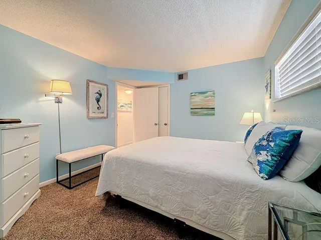 Cozy coastal guest room with soft blue walls, plush carpeting, and beach-inspired decor that creates a relaxing retreat.