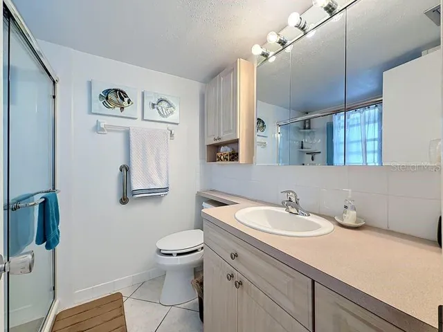 Inviting primary bathroom with warm wood cabinetry, soft lighting, and a relaxing coastal palette that ties the home's style together.