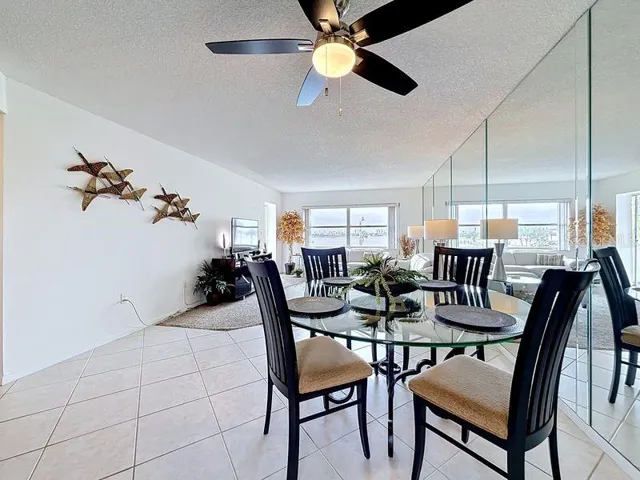 Open-concept dining area that flows seamlessly from the kitchen, featuring a glass-top table and modern coastal  decor.