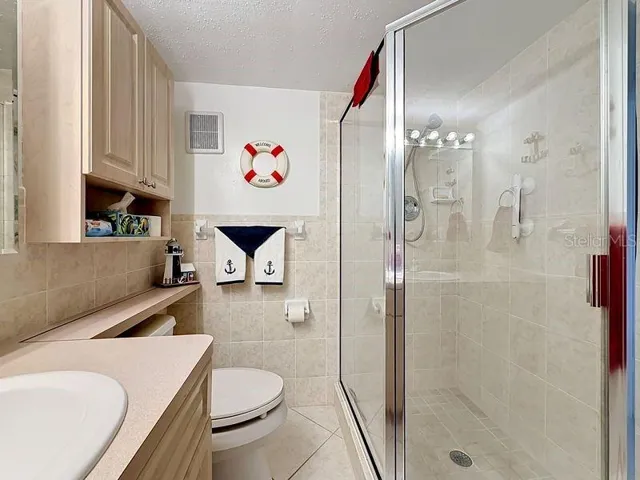 Nautical inspired guest bath with beige tile finishes, a glass-enclosed shower, and a charming coastal decor that adds personality and warmth.