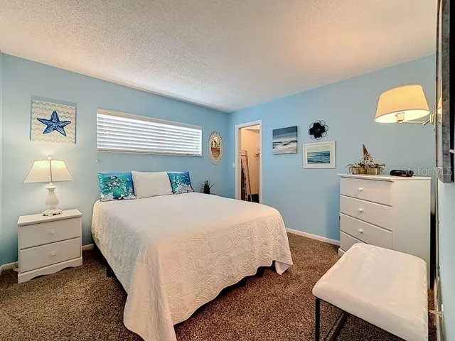 Cozy coastal guest room with soft blue walls, plush carpeting, and beach-inspired decor that creates a relaxing retreat.