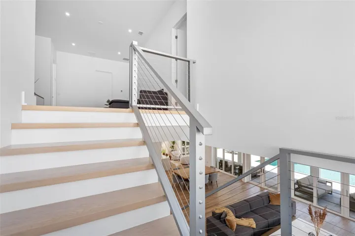 The staircase to the second floor boats solid wood treads and sleek cable railings, enhancing the minimalist design of the home.