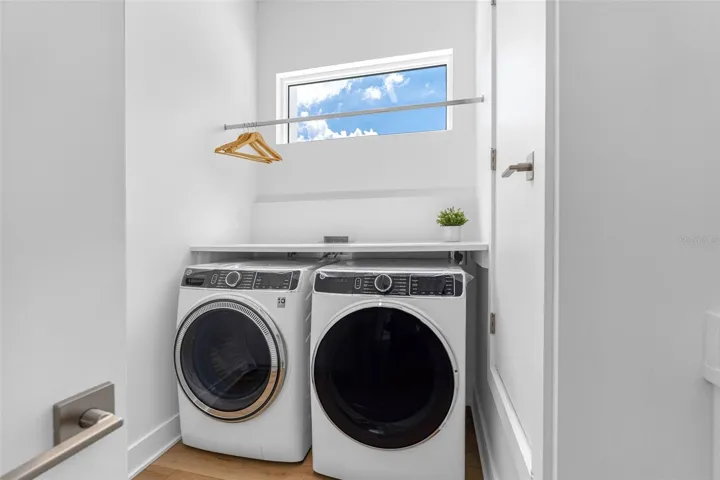 The laundry room boasts a sink, cabinetry, and a hanging rack for added convenience.