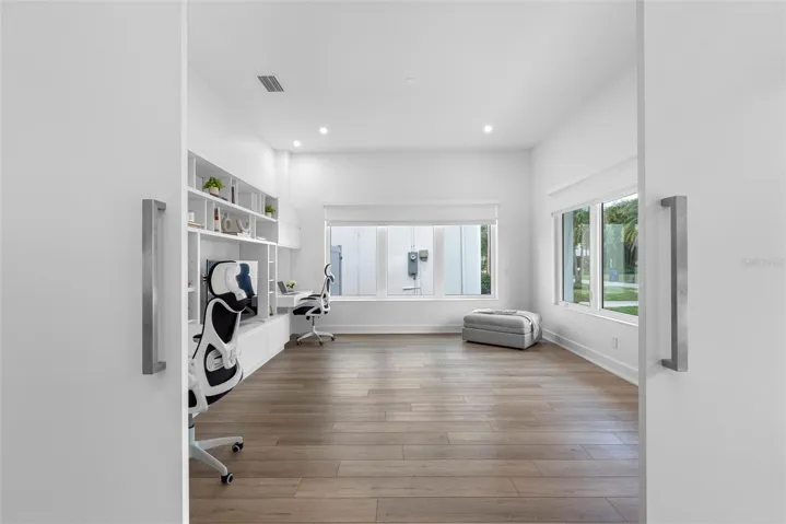 Barn doors open to a private office with built-ins, that can be used as a fifth bedroom, family room or flex room. In front of the office space, there is a full bath.