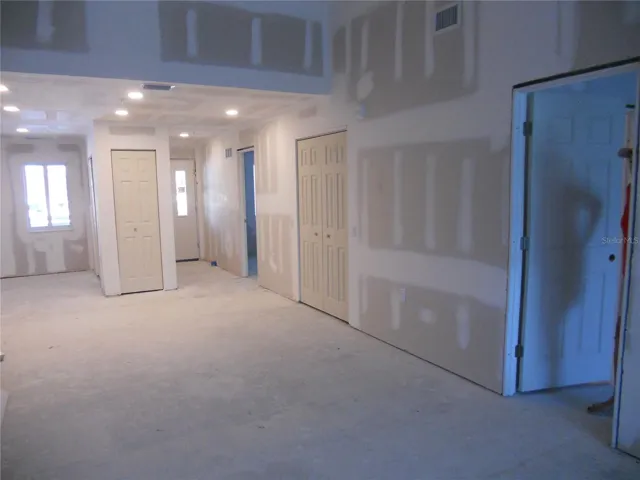 VIEW OF THE LIVING ROOM TOWARDS THE KITCHEN, DINING, FRONT ENTRY. BEDROOM DOORS ON THE RIGHT.