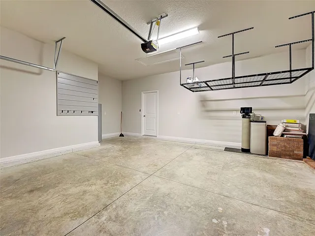 Garage with overhead storage, wall organizer system and solid garage door with opener.