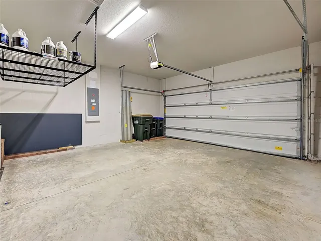 Garage with overhead storage, wall organizer system and solid garage door with opener.