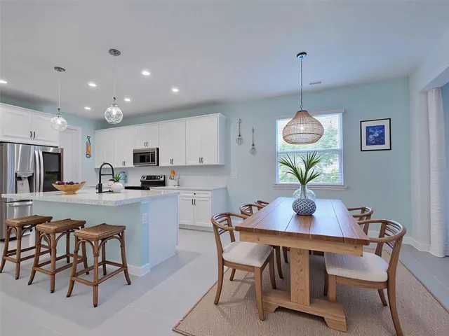 Dining area and kitchen with upgraded lighting, large island, smart refrigerator, double oven and virtual decor