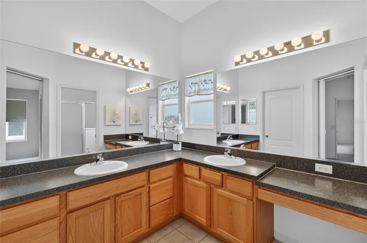 Ensuite bath complete with dual sinks, a built-in vanity, private water closet, and walk-in shower