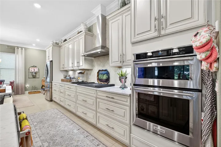 Open-concept designer kitchen featuring stainless steel appliances and a kitchen vent.