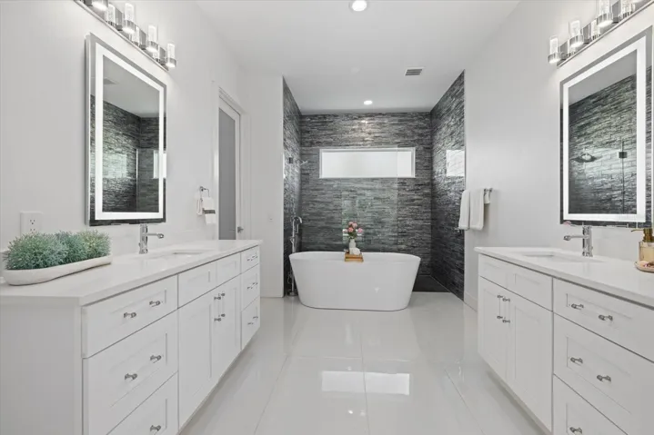 Primary bathroom with split vanity sinks and large custom closet