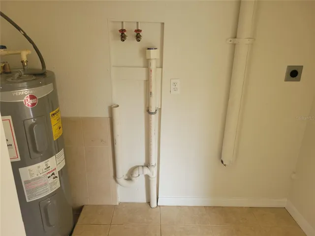 Laundry closet with a newer water heater, washer and dryer hook-ups.