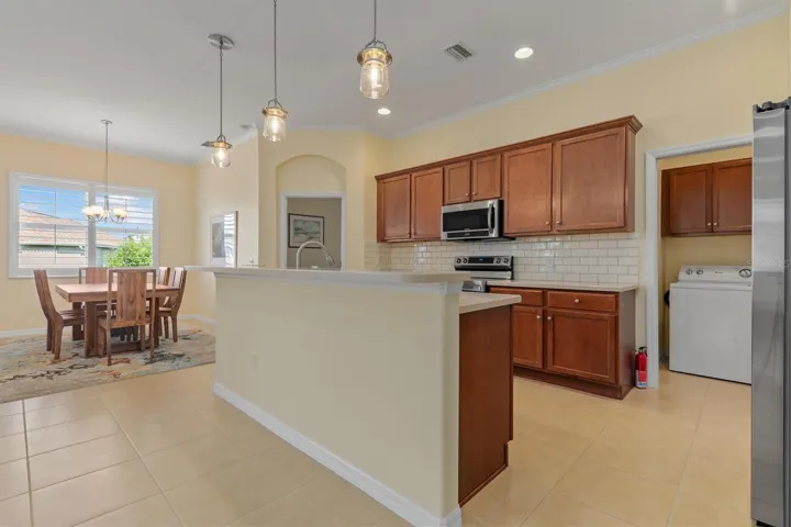 Modern pendant lighting over island. Laundry room is handy.  Sliding door between kitchen and laundry for privacy. Lots of storage above washer and dryer.