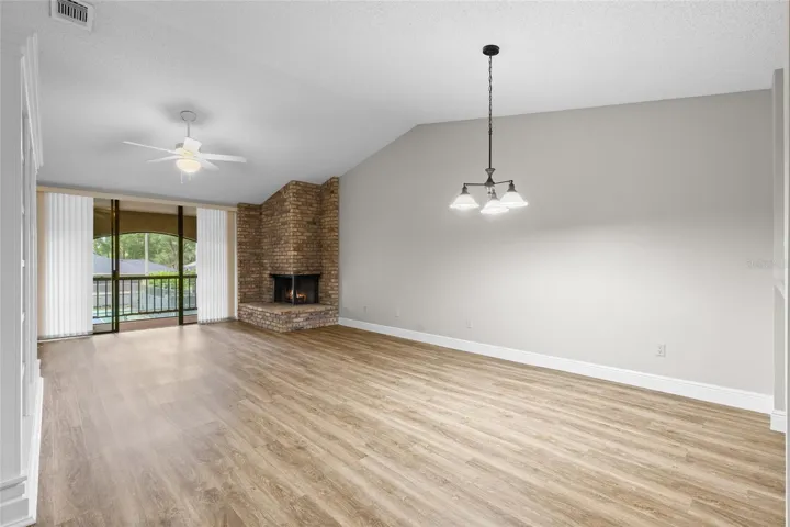Open floor plan includes high ceiling, cozy wood burning fireplace and sliding glass doors to the screened in back porch.
